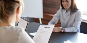 A job interview scene with a candidate sitting across the table from an interviewer who is holding a resume, illustrating a guide on how to ace your next job interview.